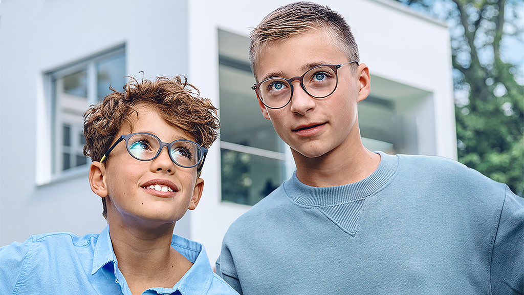 Um menino a olhar para um adolescente, ambos a usar óculos com lentes ZEISS SmartLife Monofocal Young